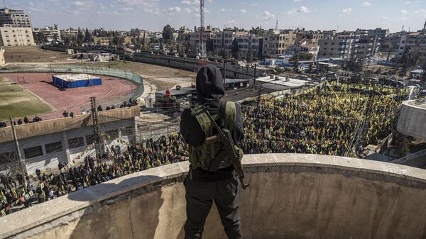 Combatente das Forças Democráticas da Síria (SDF, na sigla em inglês) observa, enquanto centenas de manifestantes marcham para exigir a libertação do líder curdo Abdullah Ocalan em Qamishli, nordeste da Síria, 15 de fevereiro de 2025. - Sputnik Brasil