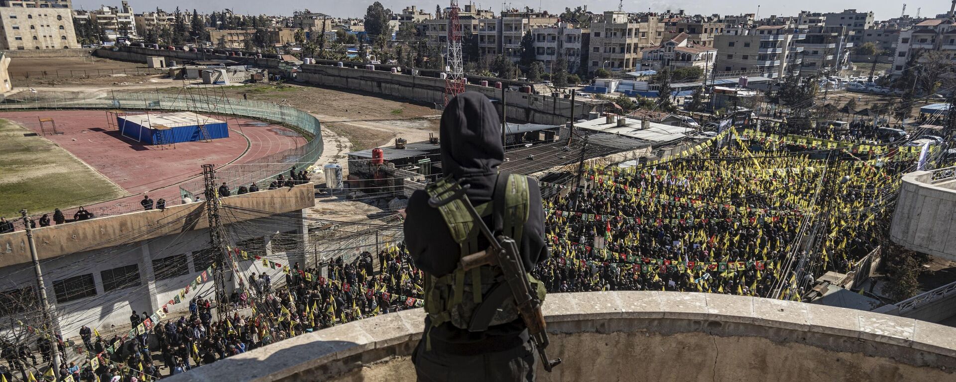 Combatente das Forças Democráticas da Síria (SDF, na sigla em inglês) observa, enquanto centenas de manifestantes marcham para exigir a libertação do líder curdo Abdullah Ocalan em Qamishli, nordeste da Síria, 15 de fevereiro de 2025. - Sputnik Brasil, 1920, 08.03.2025