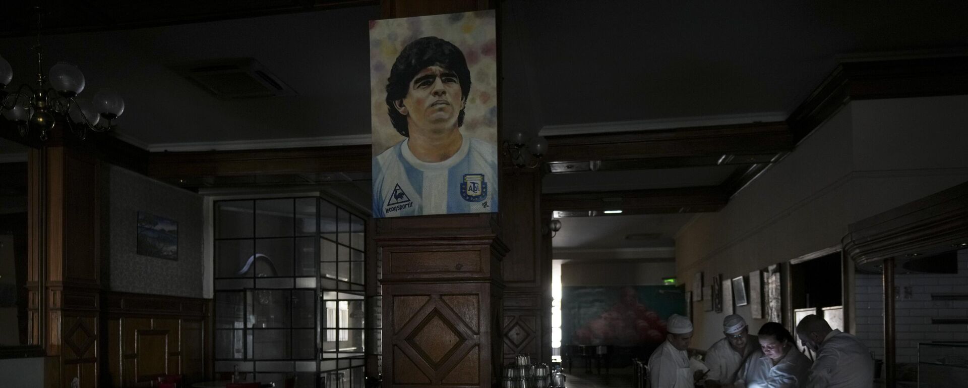 Trabalhadores em um restaurante escuro durante apagão em Buenos Aires, Argentina. 5 de março de 2025. A imagem é do falecido astro do futebol Diego Maradona. - Sputnik Brasil, 1920, 05.03.2025