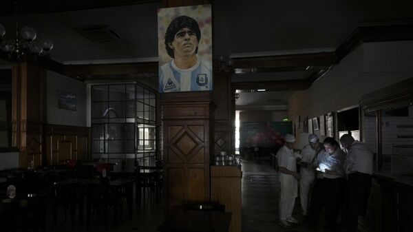 Trabalhadores em um restaurante escuro durante apagão em Buenos Aires, Argentina. 5 de março de 2025. A imagem é do falecido astro do futebol Diego Maradona. - Sputnik Brasil