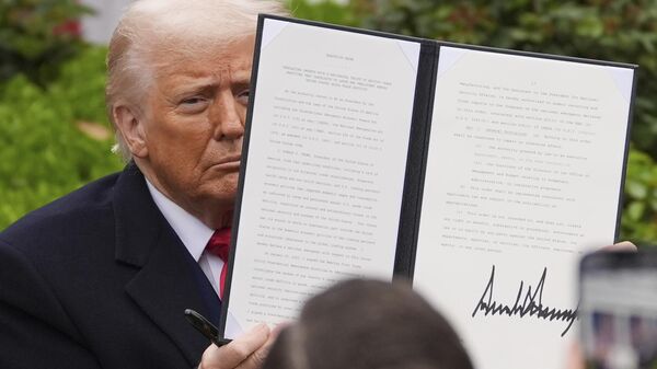 O presidente dos EUA, Donald Trump, segura uma ordem executiva assinada durante evento para anunciar novas tarifas no Rose Garden da Casa Branca. Washington, D.C., 2 de abril de 2025 - Sputnik Brasil