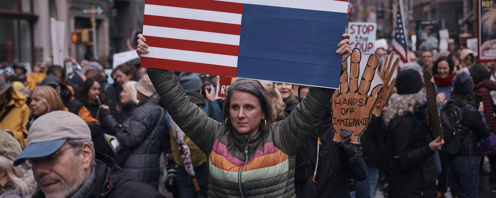 Manifestantes seguram cartazes enquanto saem às ruas e marcham durante um protesto contra Donald Trump em Nova York. EUA, 5 de abril de 2025. - Sputnik Brasil, 1920, 05.04.2025