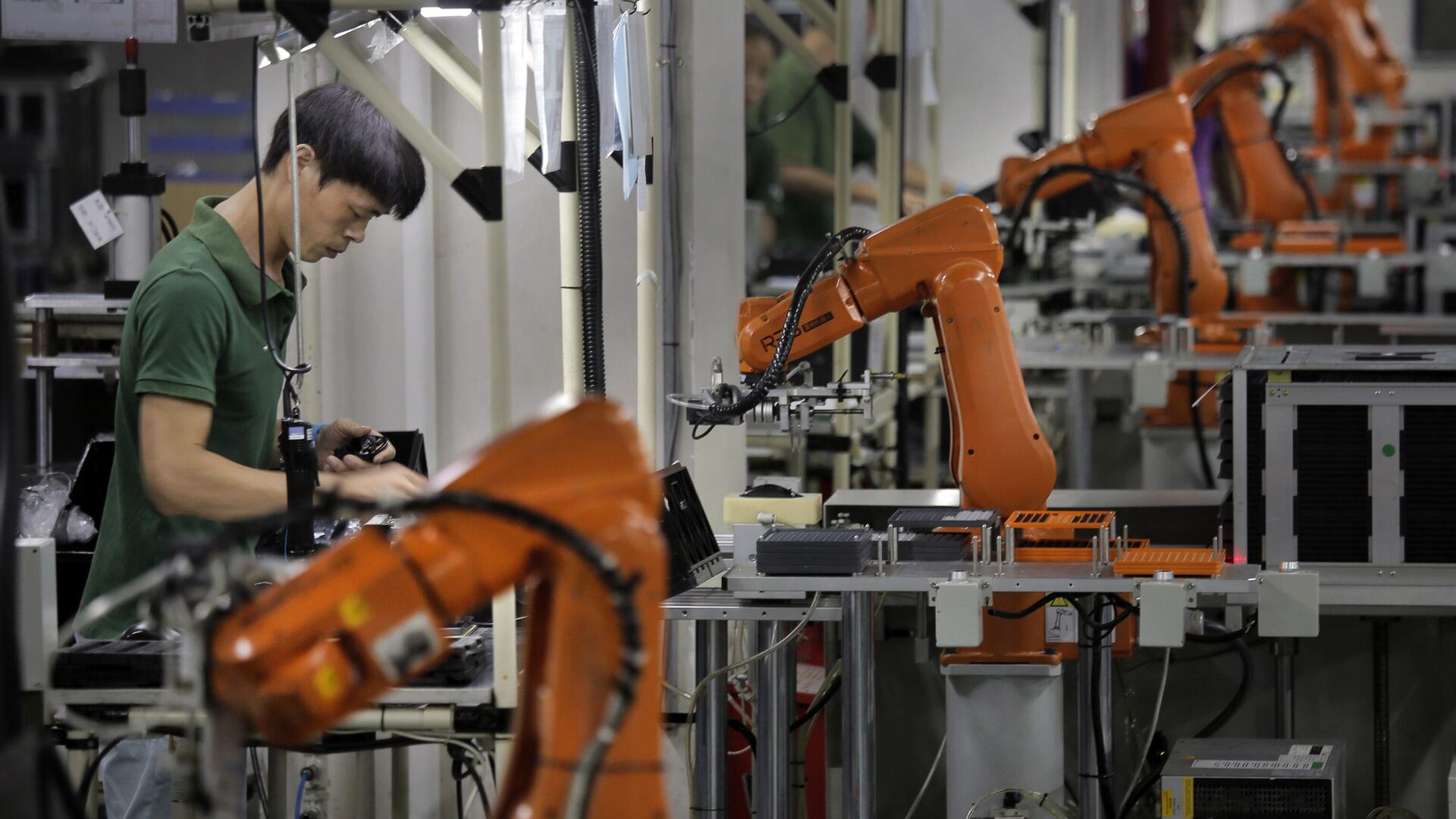 Um homem chinês trabalha em meio a braços robóticos laranja na fábrica da Rapoo Technology, em Shenzhen, cidade industrial em expansão no sul da China, 21 de agosto de 2015 Um homem chinês trabalha em meio a braços robóticos laranja na fábrica da Rapoo Technology, em Shenzhen, cidade industrial em expansão no sul da China, 21 de agosto de 2015 - Sputnik Brasil, 1920, 15.04.2025