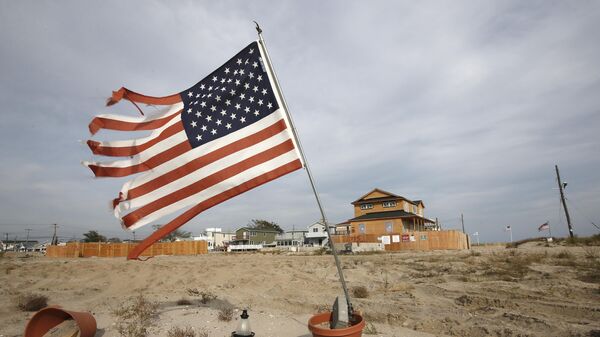 Bandeira dos EUA esfarrapada tremula na areia de um terreno baldio no bairro de Breezy Point, no Queens, em Nova York. EUA, 3 de outubro de 2013 - Sputnik Brasil
