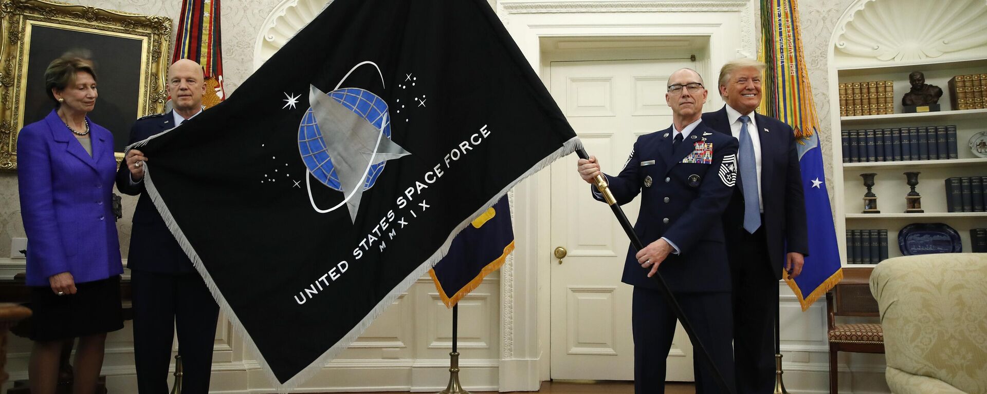 O presidente Donald Trump ocupa o cargo de chefe de Operações Espaciais da Força Espacial dos EUA. O general John Raymond, segundo da esquerda, e o sargento-chefe Roger Towberman, segundo da direita, seguram a bandeira da Força Espacial dos Estados Unidos, apresentada no Salão Oval da Casa Branca, , em Washington, 15 de maio de 2020 - Sputnik Brasil, 1920, 17.04.2025