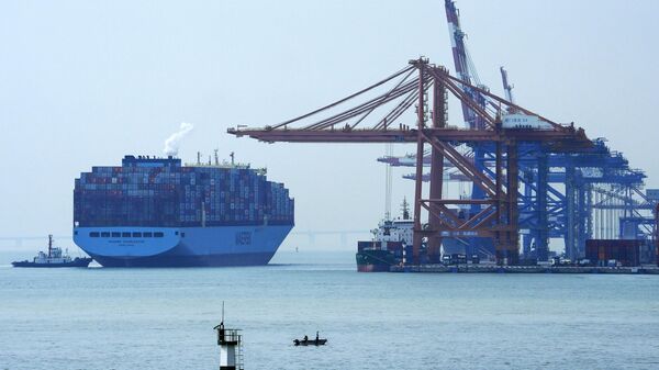 Um homem em um barco pesca enquanto um navio porta-contêineres se prepara para atracar em um porto em Xiamen, na província de Fujian, no sudeste da China, 27 de dezembro de 2023 - Sputnik Brasil