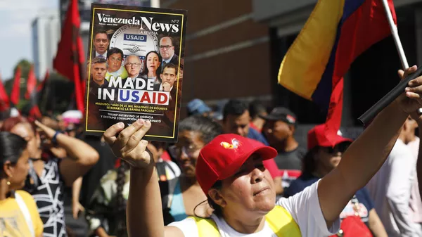 Venezuelana segura revista com manchete sobre a USAID em protesto contra sanções dos Estados Unidos. Caracas, 27 de fevereiro de 2025 - Sputnik Brasil
