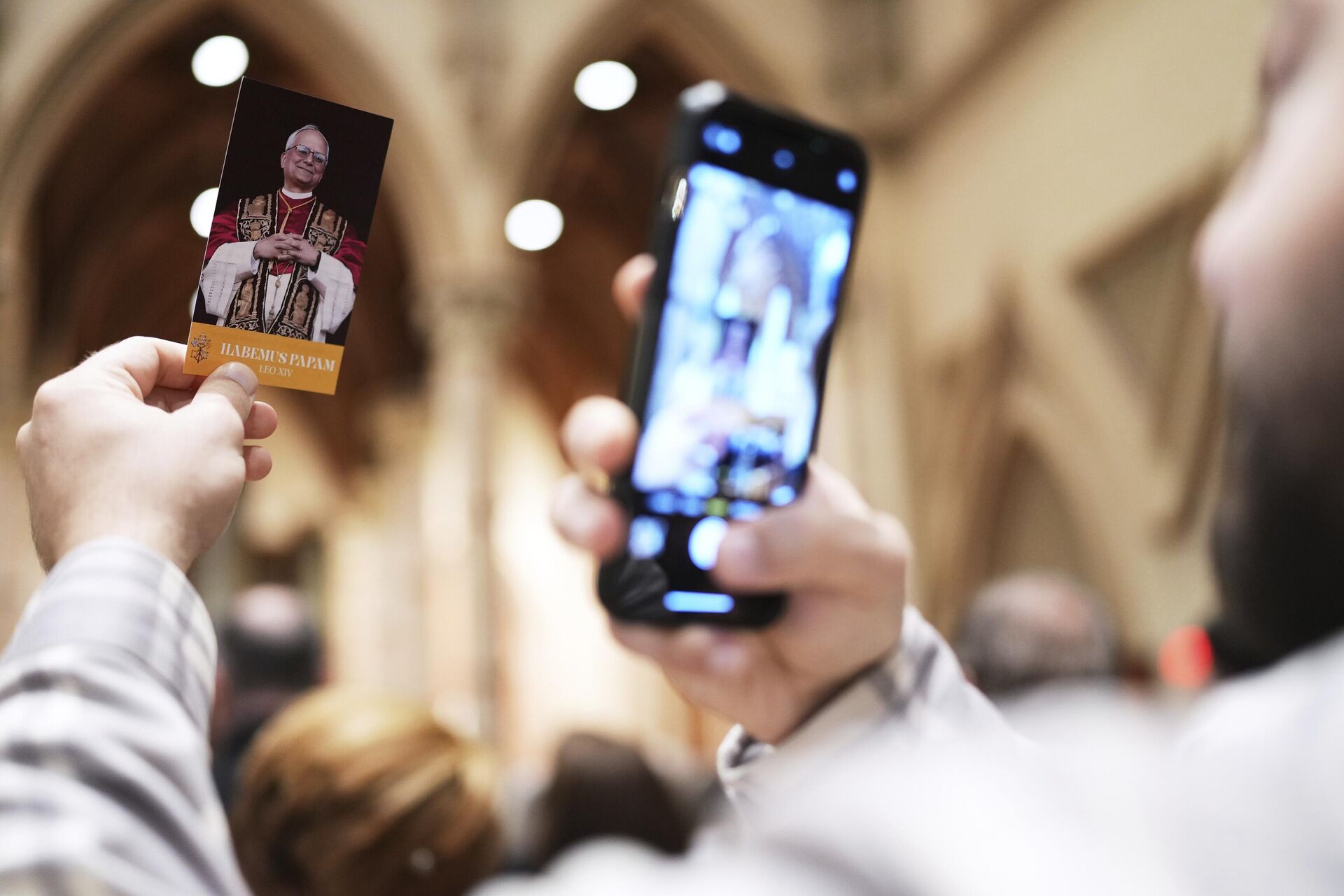 Fiel tira uma foto de um folheto com a imagem do Papa Leão XIV, durante uma em Chicago, EUA, 11 de maio de 2025 Fiel tira uma foto de um folheto com a imagem do Papa Leão XIV, durante uma em Chicago, EUA, 11 de maio de 2025