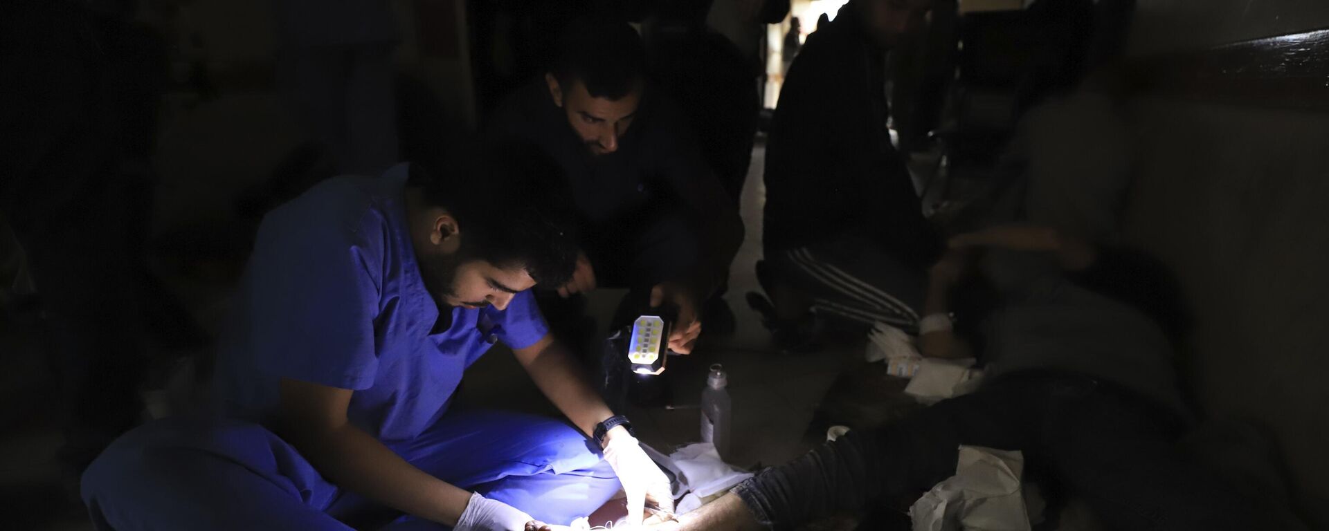 Médicos palestinos tratam um ferido usando tochas após ficarem sem energia no hospital indonésio em Beit Lahiya durante o bombardeio em andamento no norte da Faixa de Gaza, em 19 de novembro de 2023 - Sputnik Brasil, 1920, 19.05.2025