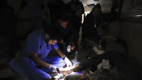 Médicos palestinos tratam um ferido usando tochas após ficarem sem energia no hospital indonésio em Beit Lahiya durante o bombardeio em andamento no norte da Faixa de Gaza, em 19 de novembro de 2023 - Sputnik Brasil