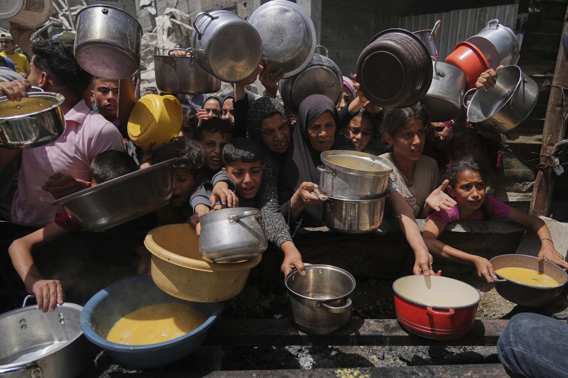 Palestinos tentam obter alimentos doados em cozinha comunitária em Jabalia, no norte da Faixa de Gaza,19 de maio de 2025 Palestinos tentam obter alimentos doados em cozinha comunitária em Jabalia, no norte da Faixa de Gaza,19 de maio de 2025