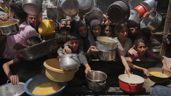 Palestinos tentam obter alimentos doados em cozinha comunitária em Jabalia, no norte da Faixa de Gaza, em 19 de maio de 2025 - Sputnik Brasil