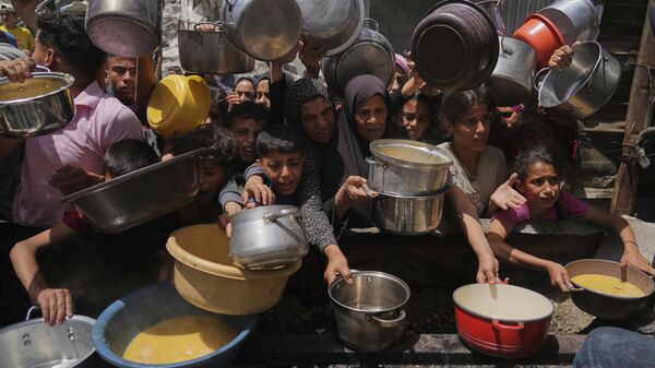 Palestinos tentam obter alimentos doados em cozinha comunitária em Jabalia, no norte da Faixa de Gaza, em 19 de maio de 2025 - Sputnik Brasil