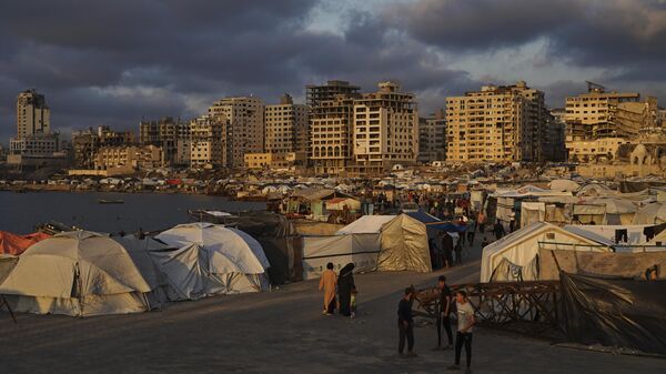 Palestinos caminham por acampamento improvisado no porto da cidade de Gaza, em 22 de maio de 2025 - Sputnik Brasil