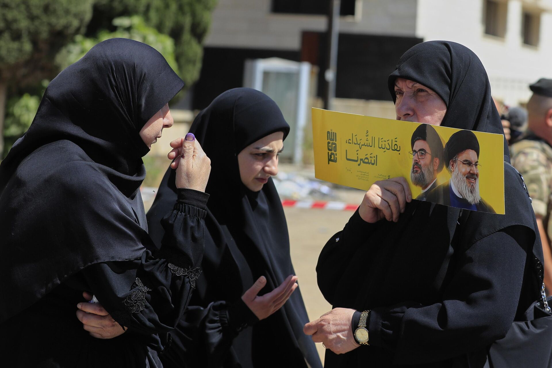 Eleitora segura cartaz com imagens do ex-líder do Hezbollah, Hassan Nasrallah, à direita, e seu primo e sucessor Hashem Safieddine, perto de uma seção eleitoral durante as eleições municipais na cidade de Nabatieh, sul do Líbano, 24 de maio de 2025 Eleitora segura cartaz com imagens do ex-líder do Hezbollah, Hassan Nasrallah, à direita, e seu primo e sucessor Hashem Safieddine, perto de uma seção eleitoral durante as eleições municipais na cidade de Nabatieh, sul do Líbano, 24 de maio de 2025
