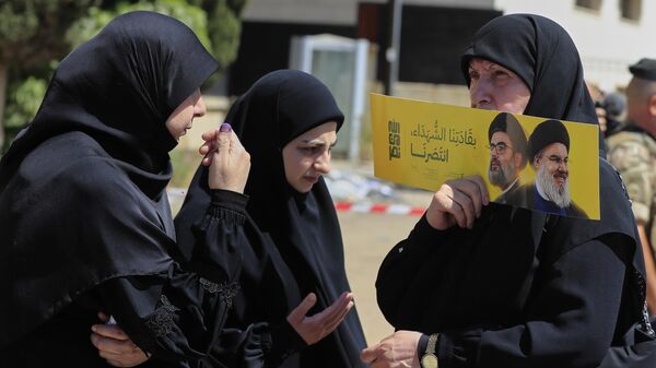 Eleitora segura cartaz com imagens do ex-líder do Hezbollah, Hassan Nasrallah, à direita, e seu primo e sucessor Hashem Safieddine, perto de uma seção eleitoral durante as eleições municipais na cidade de Nabatieh, sul do Líbano, 24 de maio de 2025 - Sputnik Brasil