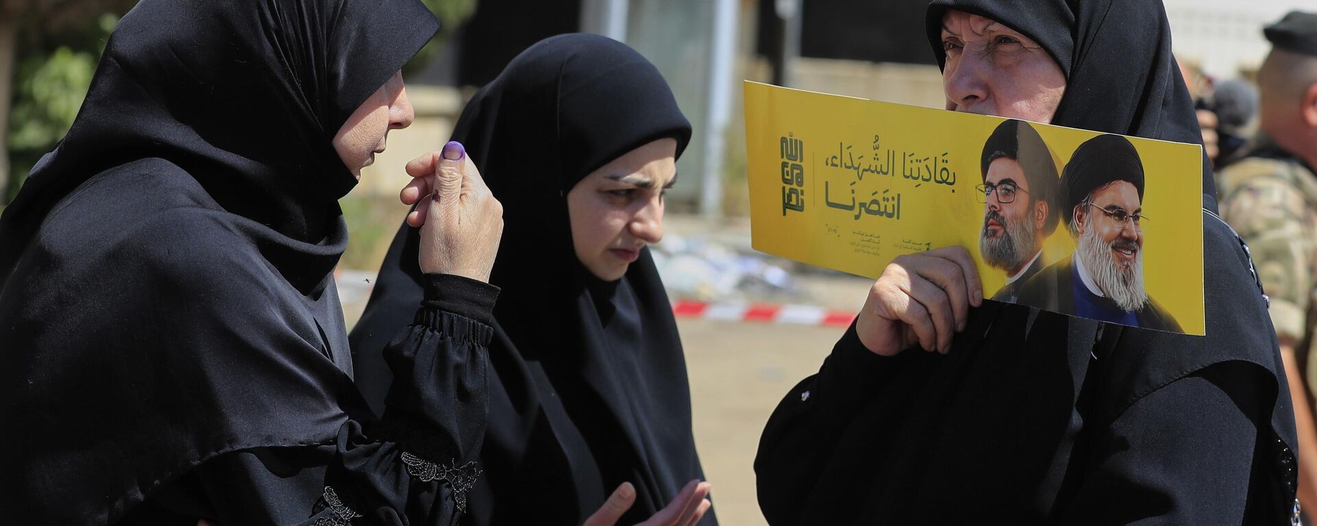 Eleitora segura cartaz com imagens do ex-líder do Hezbollah, Hassan Nasrallah, à direita, e seu primo e sucessor Hashem Safieddine, perto de uma seção eleitoral durante as eleições municipais na cidade de Nabatieh, sul do Líbano, 24 de maio de 2025 - Sputnik Brasil, 1920, 18.06.2025