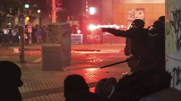 Polícia se guarda de projéteis durante os protestos contra as batidas anti-imigração do governo Trump, em Los Angeles - Sputnik Brasil