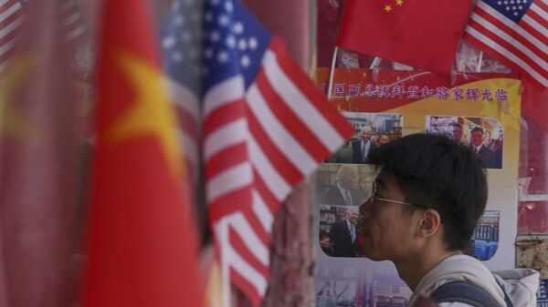 Homem entra em uma loja de produtos exibindo bandeiras nacionais da China e dos Estados Unidos, em Pequim, 3 de abril de 2025 - Sputnik Brasil