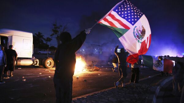 Um manifestante agita uma bandeira norte-americana e mexicana durante um protesto em Compton, Califórnia, depois que autoridades federais de imigração realizaram operações, 7 de junho de 2025 - Sputnik Brasil