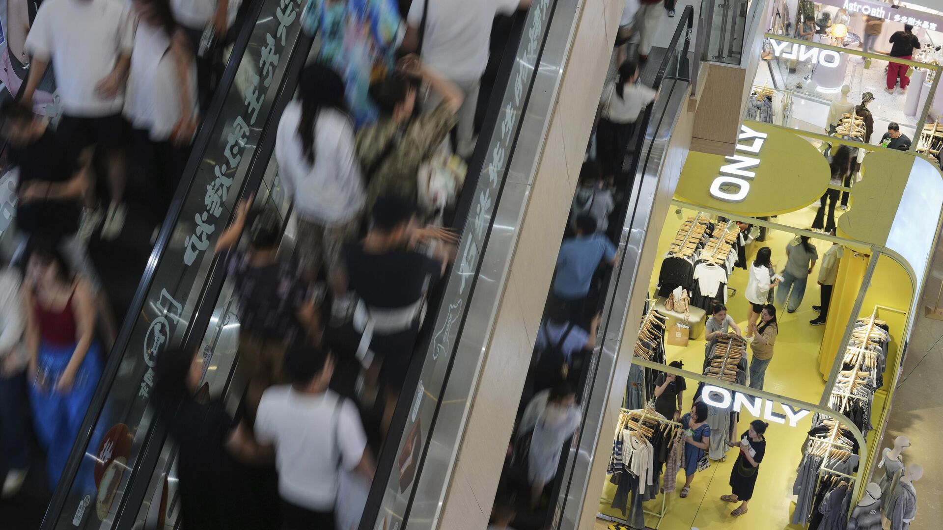 Pessoas sobem escadas rolantes enquanto compradores, à direita no andar de baixo, selecionam roupas em uma loja dentro de um shopping em Pequim, 13 de julho de 2025 Pessoas sobem escadas rolantes enquanto compradores, à direita no andar de baixo, selecionam roupas em uma loja dentro de um shopping em Pequim, 13 de julho de 2025 - Sputnik Brasil, 1920, 15.07.2025