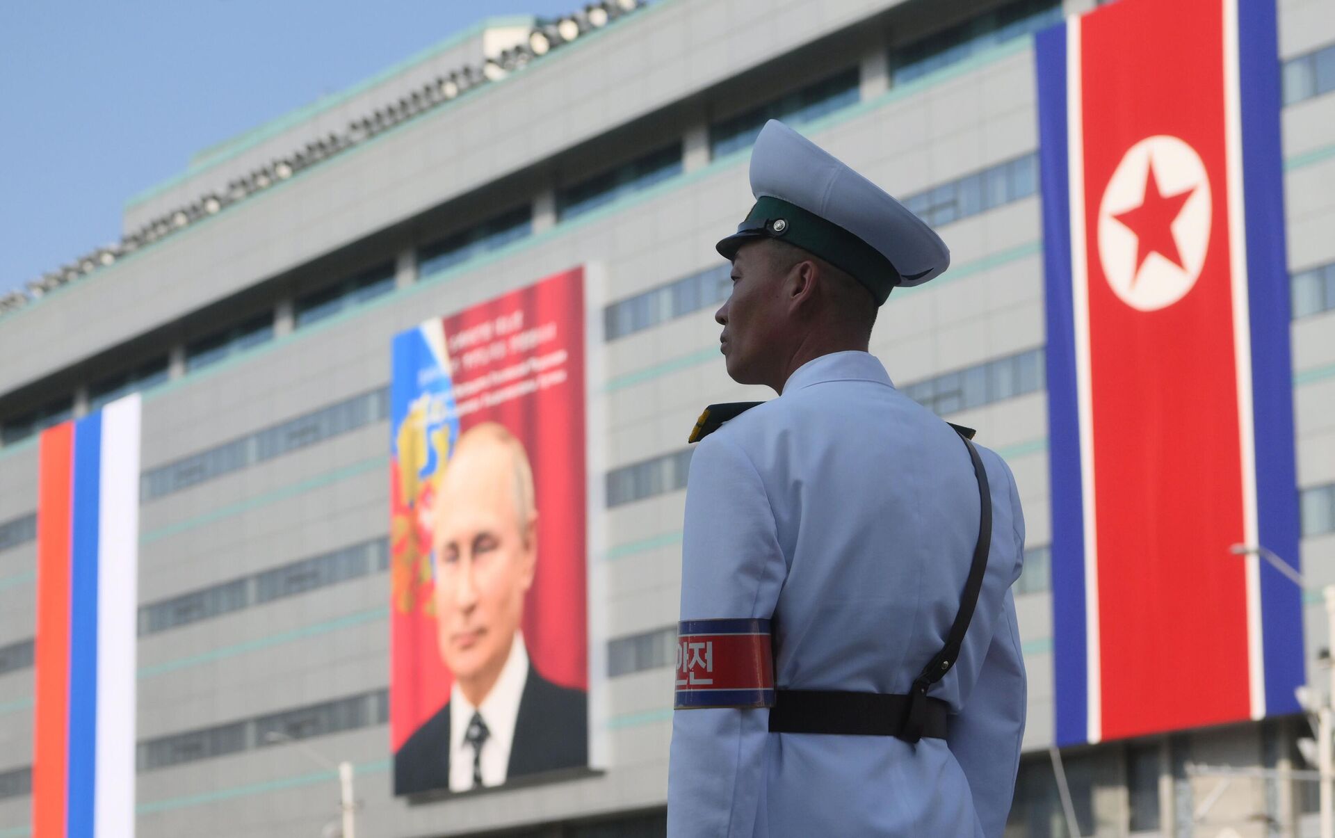 Um guarda em frente a um prédio com um retrato do presidente russo Vladimir Putin em Pyongyang, Coreia do Norte, 18 de junho de 2024 