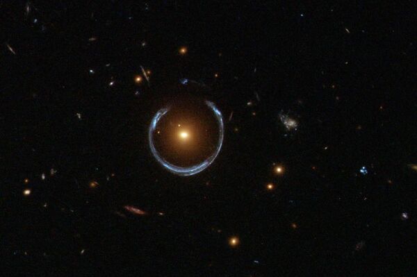 Esta interessante galáxia fotografada pelo Telescópio Espacial Hubble da NASA faz parte de um grupo de galáxias chamado Galáxias Vermelhas Luminosas. Ela tem uma massa incomumente grande, cerca de dez vezes a massa da Via Láctea. No entanto, é na verdade a forma de ferradura azul que circunscreve a galáxia vermelha que é o verdadeiro prêmio nesta imagem - Sputnik Brasil