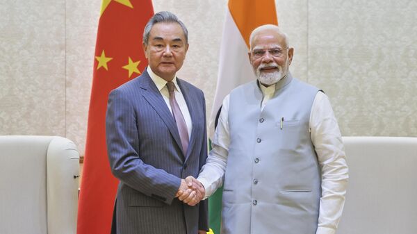 O primeiro-ministro indiano Narendra Modi (D), aperta a mão do ministro das Relações Exteriores chinês Wang Yi, em Nova Deli, Índia, 19 de agosto de 2025 - Sputnik Brasil