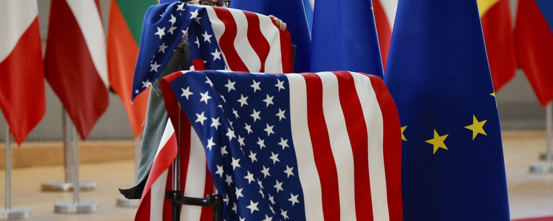 Um membro do protocolo ajusta as bandeiras dos EUA e da UE antes da chegada do secretário de Estado dos EUA, Antony Blinken, e do presidente do Conselho Europeu, Charles Michel, durante uma reunião extraordinária dos ministros das Relações Exteriores da UE no edifício do Conselho Europeu em Bruxelas, sexta-feira, 4 de março de 2022. - Sputnik Brasil, 1920, 21.08.2025