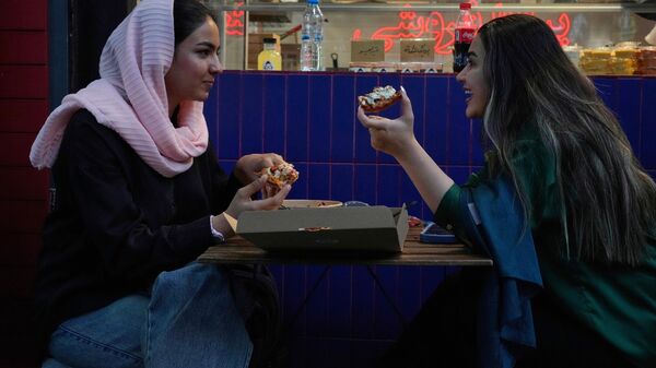 Mulheres comem pizza na área externa de um restaurante no norte de Teerã. Irã, 2 de junho de 2025 - Sputnik Brasil