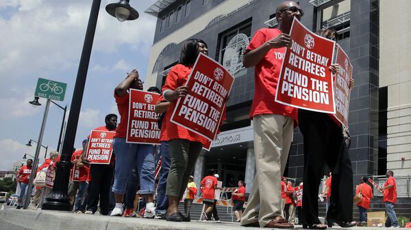 Manifestantes carregam cartazes de protesto enquanto marcham contra a decisão de usar o pagamento de pensões para equilibrar o orçamento em Trenton, Nova Jersey. EUA, 25 de junho de 2014 - Sputnik Brasil