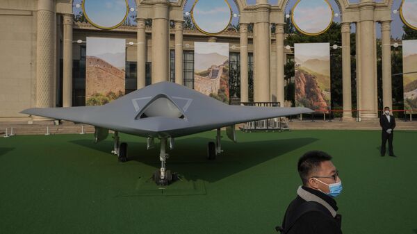 Um visitante usando máscara facial caminha ao lado do drone furtivo chinês GJ-11, em exposição que destaca o presidente Xi Jinping e as conquistas da China sob sua liderança no Salão de Exposições de Pequim, onde será realizado o 20º Congresso do Partido Comunista da China, 12 de outubro de 2022 - Sputnik Brasil