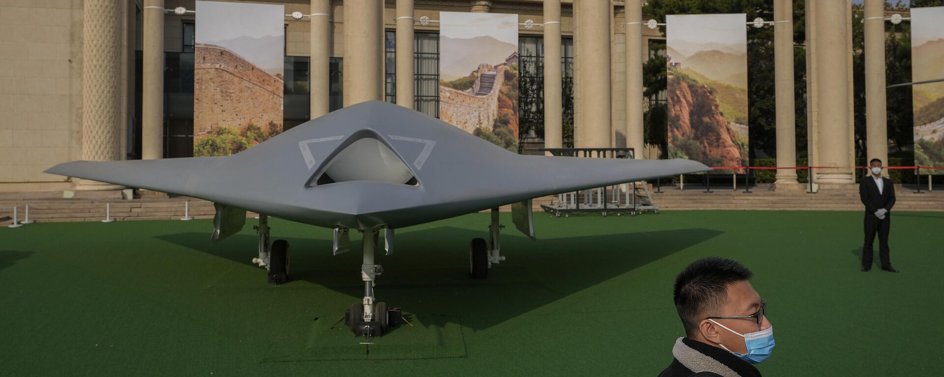 Um visitante usando máscara facial caminha ao lado do drone furtivo chinês GJ-11, em exposição que destaca o presidente Xi Jinping e as conquistas da China sob sua liderança no Salão de Exposições de Pequim, onde será realizado o 20º Congresso do Partido Comunista da China, 12 de outubro de 2022 Um visitante usando máscara facial caminha ao lado do drone furtivo chinês GJ-11, em exposição que destaca o presidente Xi Jinping e as conquistas da China sob sua liderança no Salão de Exposições de Pequim, onde será realizado o 20º Congresso do Partido Comunista da China, 12 de outubro de 2022 - Sputnik Brasil, 1920, 27.09.2025