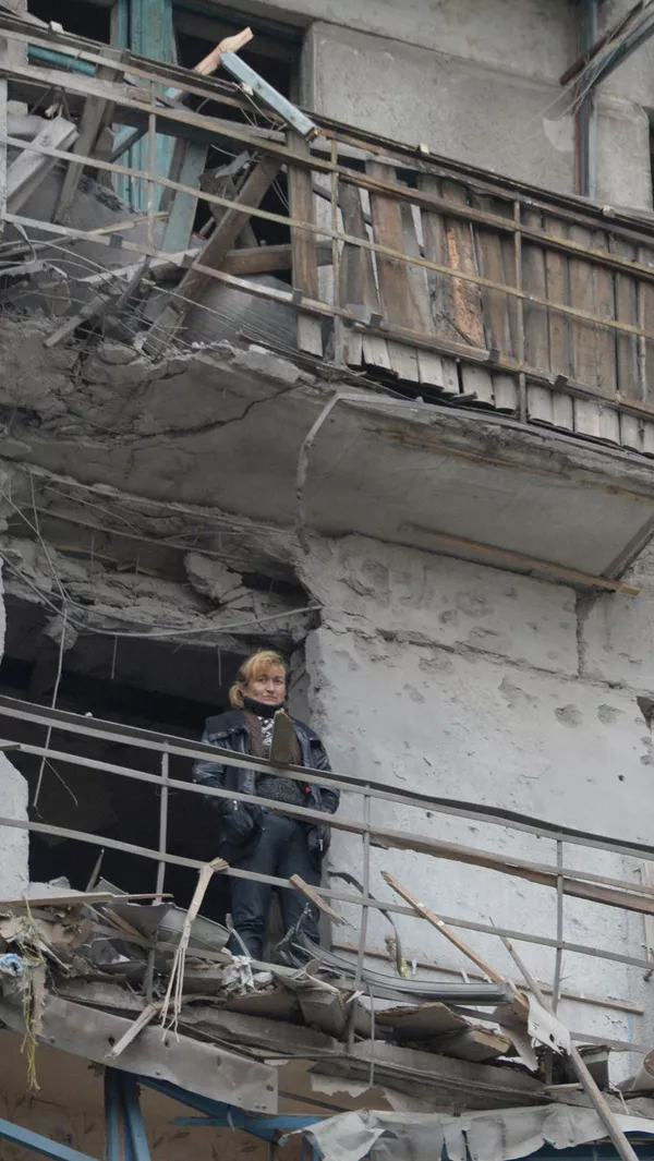 Uma mulher na varanda de uma casa bombardeada pelo exército ucraniano. Uma mulher na varanda de uma casa bombardeada pelo exército ucraniano. - Sputnik Brasil