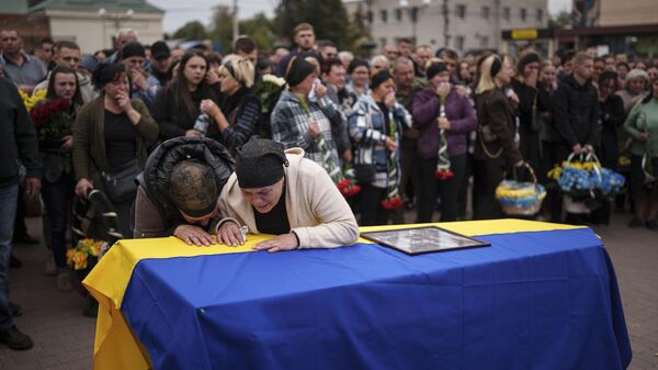 Mãe com sua família choram sobre o caixão de seu filho, combatente ucraniano  que foi eliminado pelas forças russas na linha de frente. - Sputnik Brasil