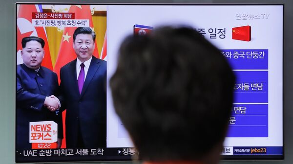 Uma mulher assiste a um programa de notícias na TV sobre o encontro entre o líder norte-coreano Kim Jong-un e o presidente chinês Xi Jinping na Estação Ferroviária de Seul, em Seul, Coreia do Sul, 28 de março de 2018 - Sputnik Brasil