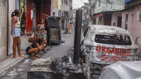 Moradores em meio a carros incendiados um dia após a megaoperação das polícias Militar e Civil que provocou mais de 120 mortes nos complexos da Penha e do Alemão. Rio de Janeiro (RJ), 29 de outubro de 2025 - Sputnik Brasil