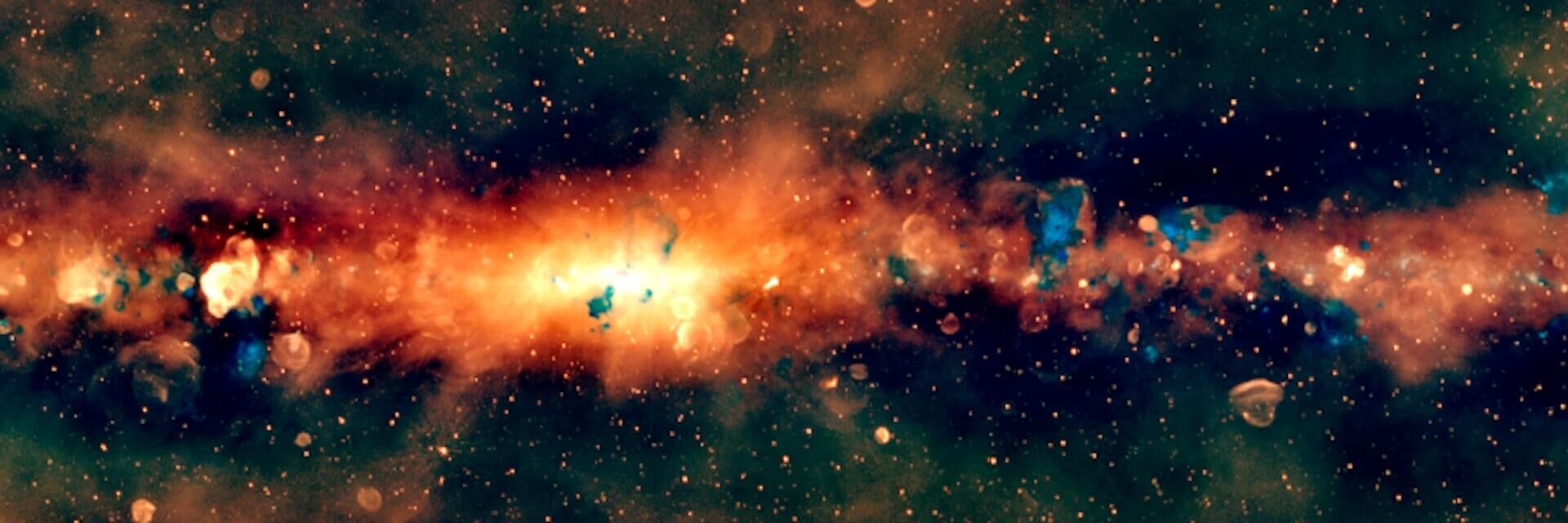 Um novo retrato em rádio do centro da Via Láctea, visto pelo Murchison Widefield Array. A galáxia é representada em cores de rádio, onde o laranja denota as frequências mais baixas, o verde as frequências intermediárias e o azul as mais altas Um novo retrato em rádio do centro da Via Láctea, visto pelo Murchison Widefield Array. A galáxia é representada em cores de rádio, onde o laranja denota as frequências mais baixas, o verde as frequências intermediárias e o azul as mais altas