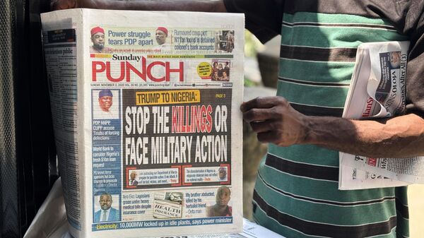 Vendedor ambulante vende jornais locais com manchetes que fazem referência aos comentários do presidente dos EUA, Donald Trump, sobre a Nigéria, em uma rua de Lagos. Nigéria, 2 de novembro de 2025 - Sputnik Brasil