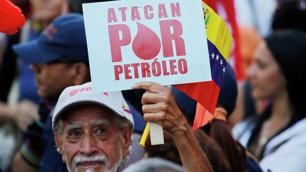 Manifestante segura placa com os dizeres em espanhol Eles atacam por petróleo, durante marcha convocada pelo governo em apoio à estatal petrolífera PDVSA, em Caracas. Venezuela, 31 de janeiro de 2019 - Sputnik Brasil