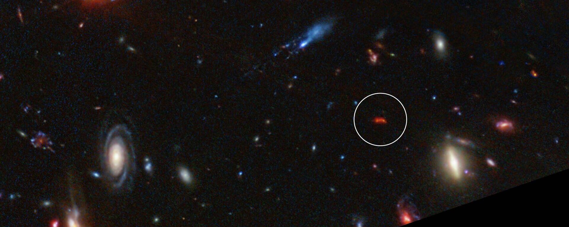 A galáxia Y1 brilha em vermelho intenso devido à poeira aquecida por novas estrelas - Sputnik Brasil, 1920, 12.11.2025