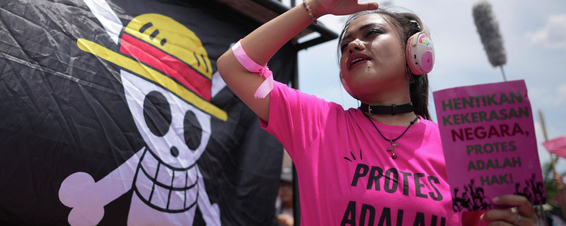 Ativista segura cartaz e ao fundo uma bandeira do personagem One Piece. - Sputnik Brasil, 1920, 14.11.2025