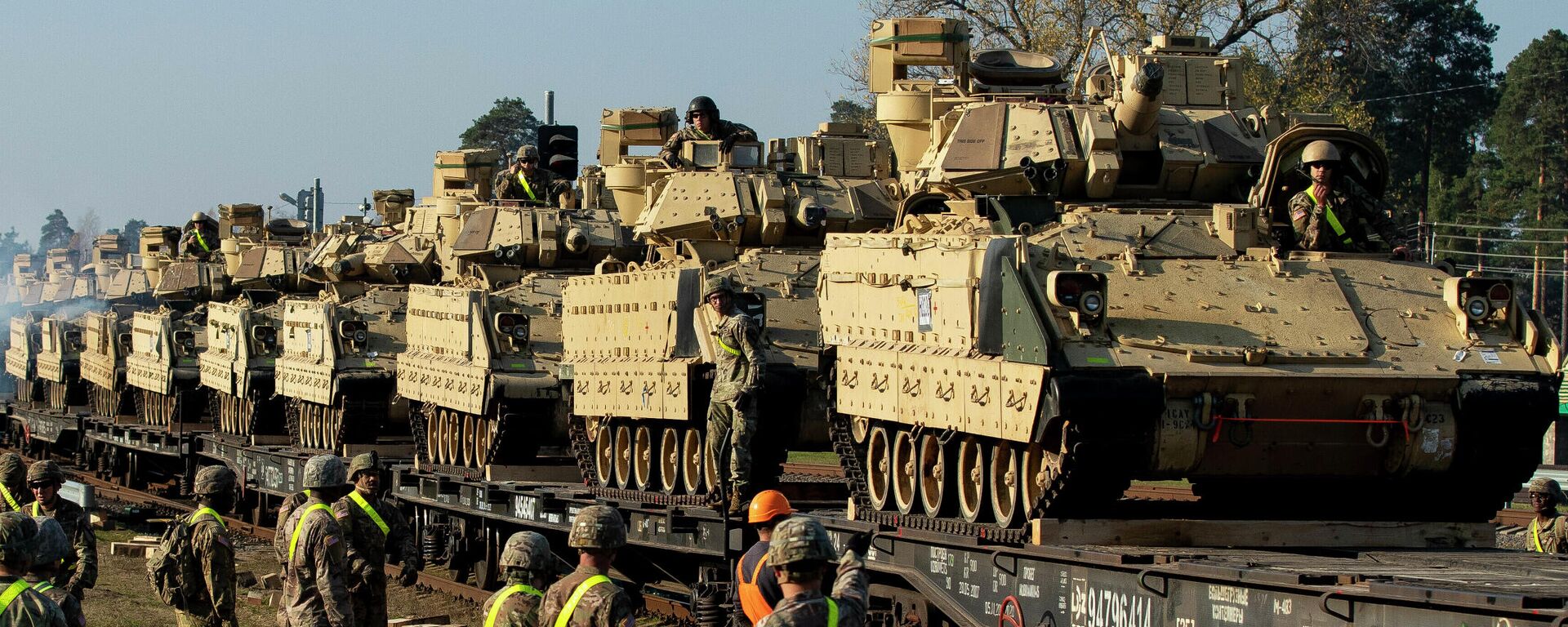 Membros do 1º Batalhão Blindado do 9º Regimento, 1ª Divisão do Exército dos EUA, de Fort Hood, Texas, se preparam para descarregar veículos de combate de infantaria Bradley de vagões ferroviários à estação ferroviária de Pabrade, a cerca de 50 km ao norte da capital Vilnius, Lituânia, 21 de outubro de 2019 - Sputnik Brasil, 1920, 18.11.2025
