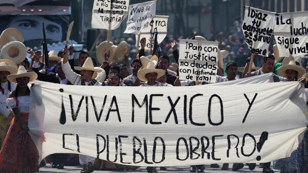 Pessoas vestidas como combatentes revolucionários carregam uma faixa que diz em espanhol Viva o México e a classe trabalhadora! durante um desfile que marca o 115º aniversário da Revolução Mexicana no Zócalo, a praça principal da Cidade do México, 20 de novembro de 2025 - Sputnik Brasil