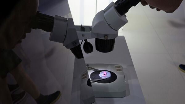 Visitante de exposição em Pequim observa chip em um microscópio do projeto Tsinghua Unigroup, controlado pelo Estado chinês, que se tornou um campeão nacional das ambições nacionais no setor de semicondutores. China, 17 de maio de 2018 - Sputnik Brasil