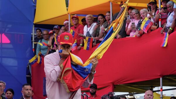 O presidente Nicolás Maduro beija a bandeira venezuelana durante a cerimônia de posse dos comitês comunitários organizados pelo governo no palácio presidencial em Caracas, Venezuela, 1º de dezembro de 2025 - Sputnik Brasil