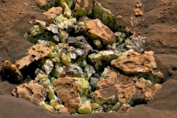 No detalhe, o frágil bloco de mineral em Marte, rompido em maio deste ano, quando o rover Curiosity acidentalmente passou por cima de sua superfície com seu corpo de 899 quilos, revelando cristais amarelos de enxofre elementar. - Sputnik Brasil
