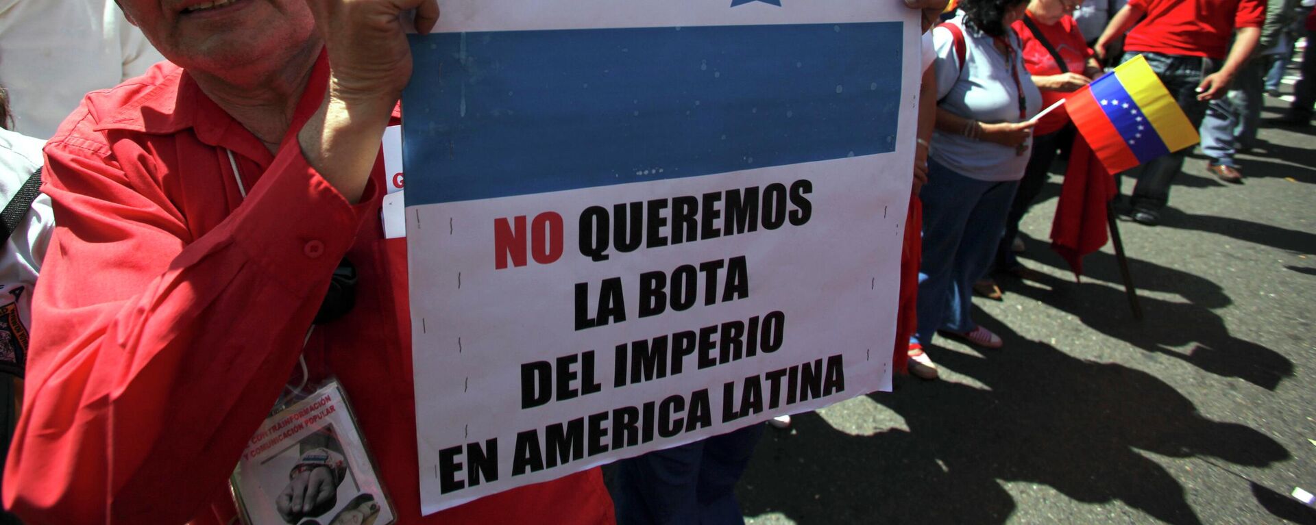 Apoiador do presidente venezuelano Hugo Chávez segura um cartaz com os dizeres em espanhol Não queremos a bota do império na América Latina durante um protesto em Caracas. Venezuela, 13 de novembro de 2009 - Sputnik Brasil, 1920, 16.12.2025