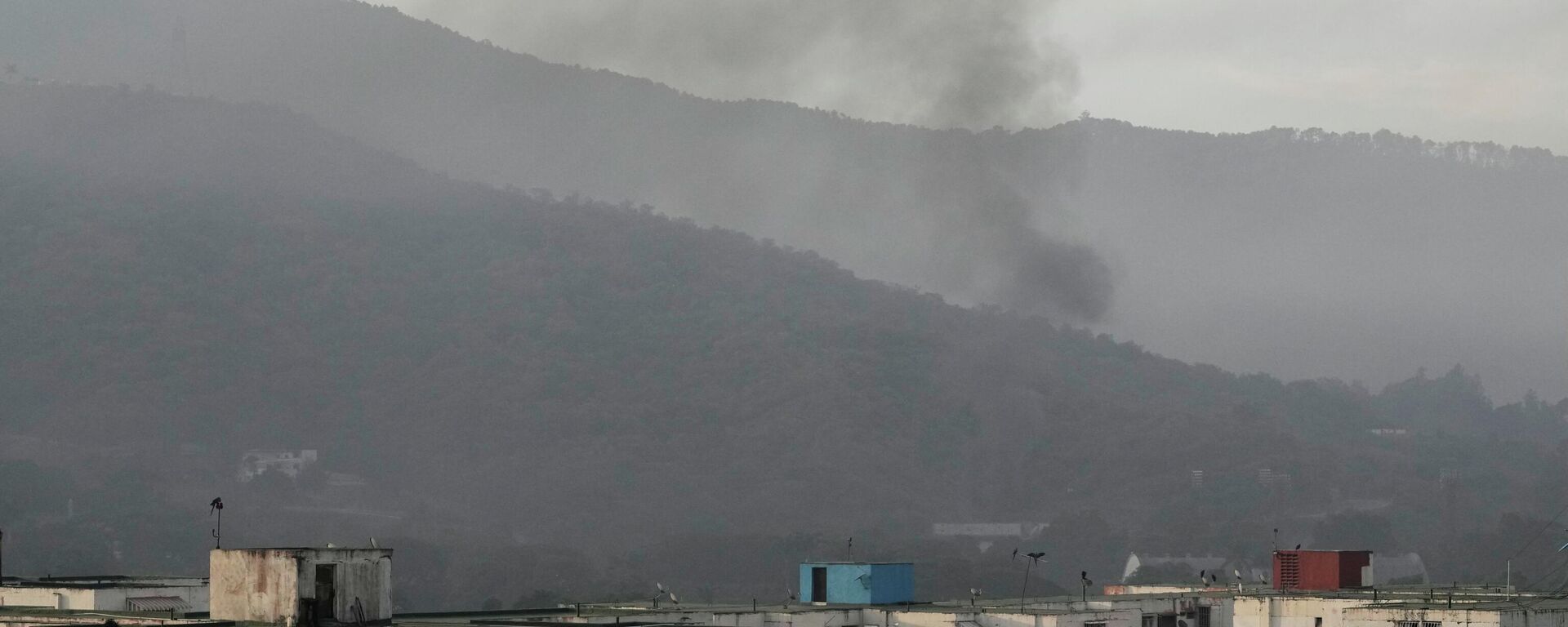 Fumaça sobe de Fuerte Tiuna, a principal guarnição militar de Caracas, na Venezuela, depois que várias explosões foram ouvidas e aeronaves varreram a área no sábado, 3 de janeiro de 2026. - Sputnik Brasil, 1920, 03.01.2026