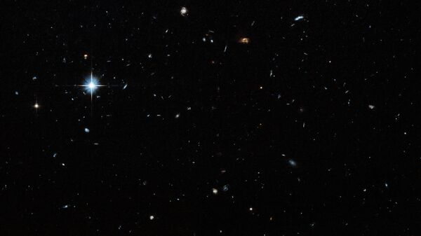 Um campo escuro com estrelas e galáxias de vários tamanhos espalhadas por toda a imagem. Uma estrela particularmente brilhante é visível na região superior esquerda - Sputnik Brasil